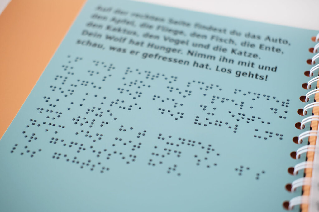 Aufgeschlagenes Ringbuch mit Braille-Vollschrift und Großdruck