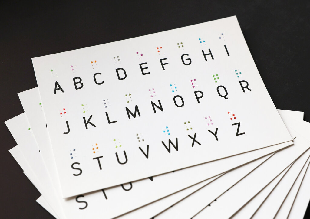 Ein Stapel Postkarten mit tastbarem Braillealphabet im Relieflack