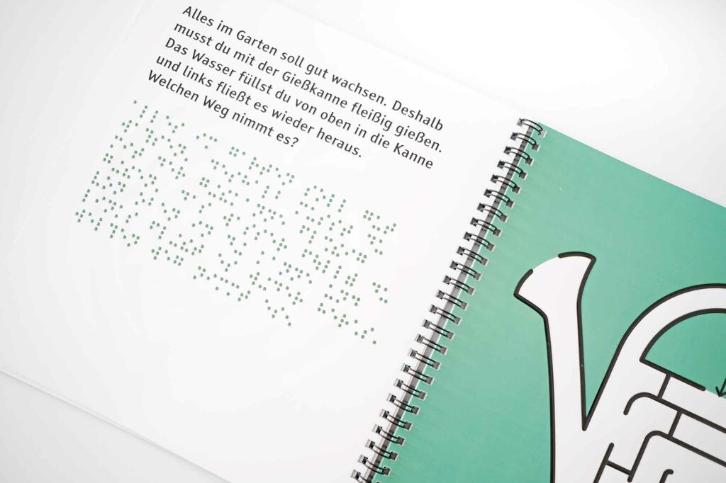 Aufgeschlagenes Ringbuch mit Großdruck, Braille-Lack und Gießkanne in Lack-Konturen