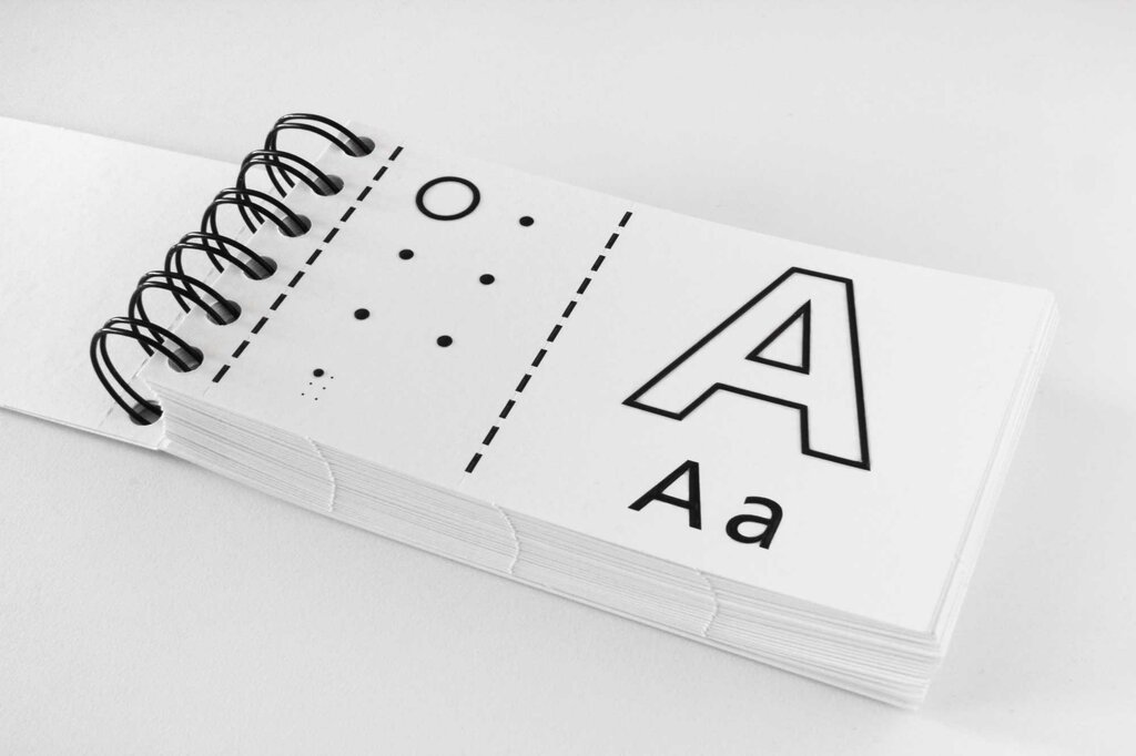 Aufgeschlagenes Ringbuch mit Buchstabe A in Brailleschrift und Großdruck in Groß- und Kleinschreibung