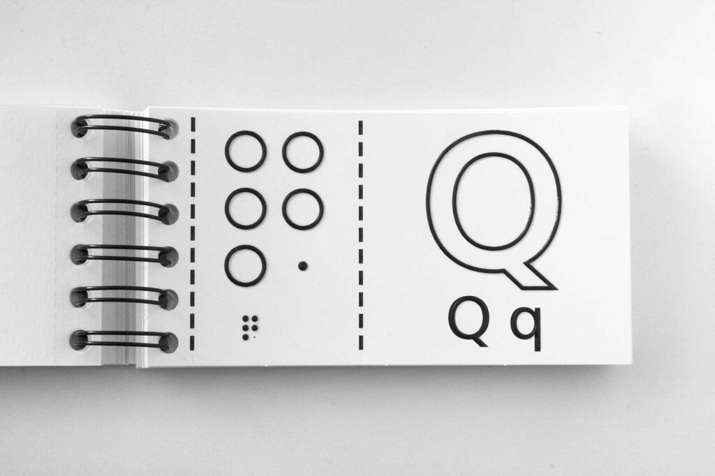Aufgeschlagenes Ringbuch mit Buchstabe Q in Brailleschrift und Großdruck in Groß- und Kleinschreibung