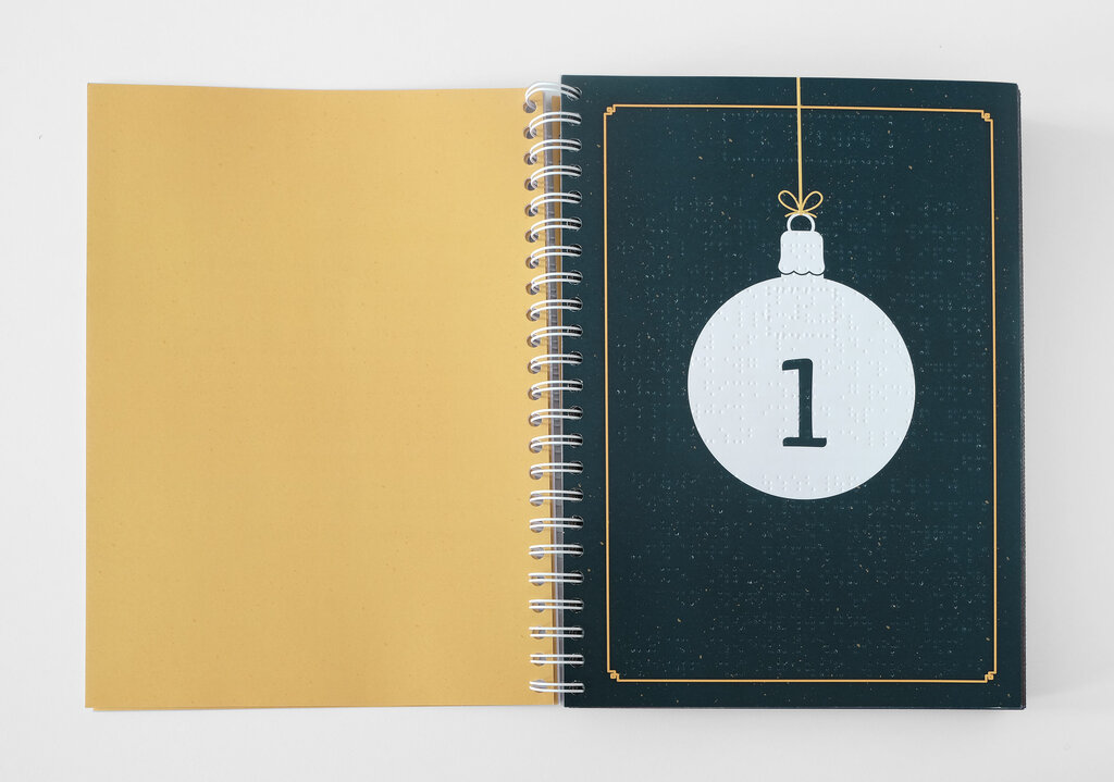 Aufgeschlagenes Ringbuch mit weißer nummerierter Weihnachtsbaumkugel auf petrolfarbenem Untergrund