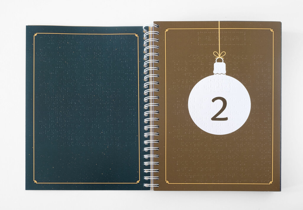 Aufgeschlagenes Ringbuch mit weißer nummerierter Weihnachtsbaumkugel auf braunem Untergrund