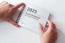 Vergrößerungsansicht: Zwei Hände halten den Taschenkalender Maxi 2025 in Brailleschrift