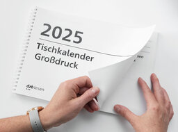 Vergrößerungsansicht: Zwei Hände blättern im Großdruck-Tischkalender 2025 im Querformat