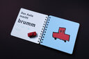 Vergrößerungsansicht: Aufgeklapptes Ringbuch, linke Buchseite mit Großdruck und Brailleschrift, rechte Buchseite mit taktiler Abbildung eines roten Autos