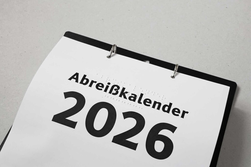 Detailansicht vom Abreißkalender 2026 mit Beschriftung in Großdruck und Brailleschrift mit Aufhängung