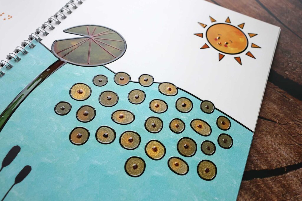 Aufgeklapptes Ringbuch mit Text in Großdruck und Braille-Schrift sowie taktilen Illustrationen 