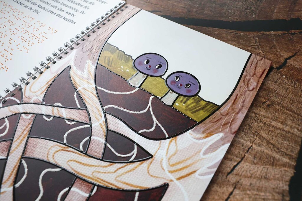 Aufgeklapptes Ringbuch mit Text in Großdruck und Braille-Schrift sowie taktilen Illustrationen