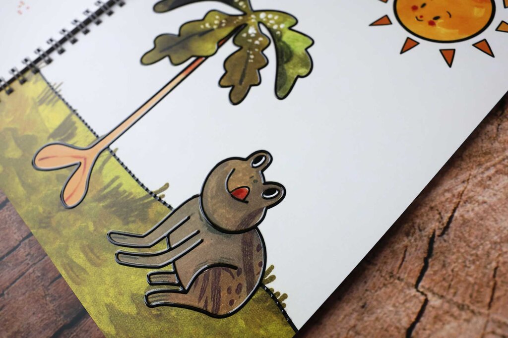 Aufgeklapptes Ringbuch mit taktilen Illustrationen vom Baumsetzling, Frosch und Sonne