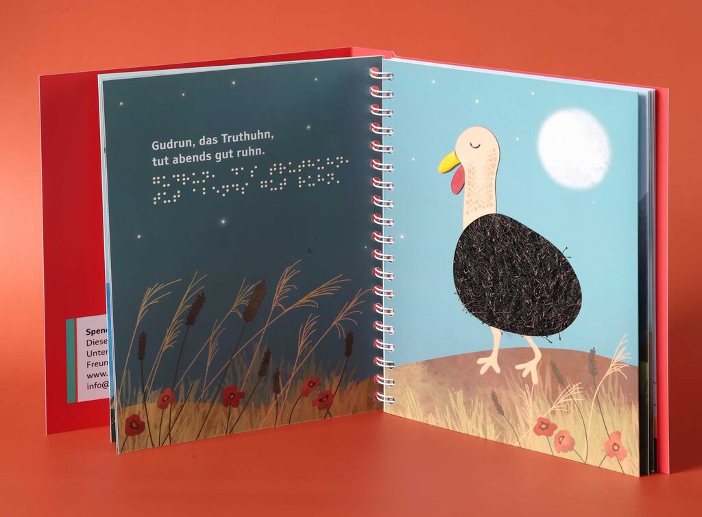 Taktil gestaltete Doppelseite mit Zungenbrecher in Großdruck und Brailleschrift und Truthenne aus verschiedenen tastbaren Materialien