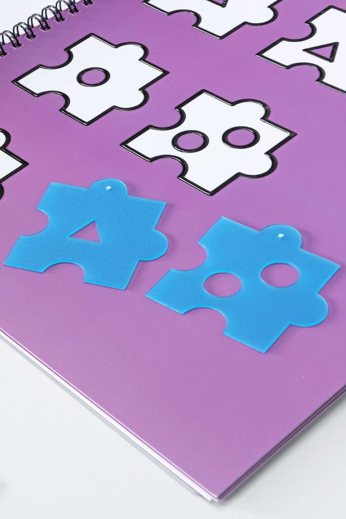 Zwei Puzzleteile aus Kunststoff liegen auf der aufgeklappten Buchseite des Rätselhefts, das mit fühlbaren Lackkonturen in Form der Puzzleteile bedruckt ist.