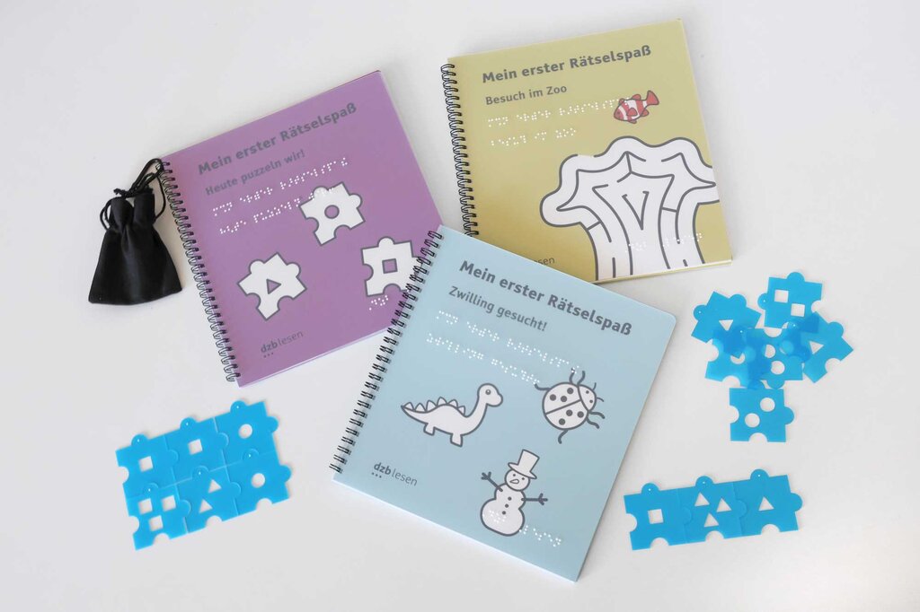 Drei unterschiedliche Rätselhefte liegen ausgebreitet auf einem weißen Hintergrund.
