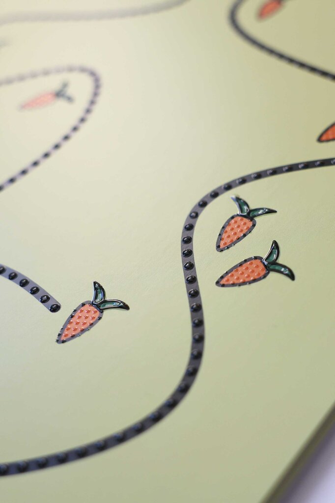 Detailaufnahme von taktil gedruckten Mohrrüben, die entlang einer geschlängelten Punktelinie angeordnet sind