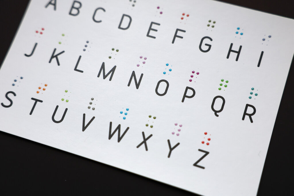 Postkarte mit tastbarem Brailleschrift-Alphabet in farbigem Lackdruck.