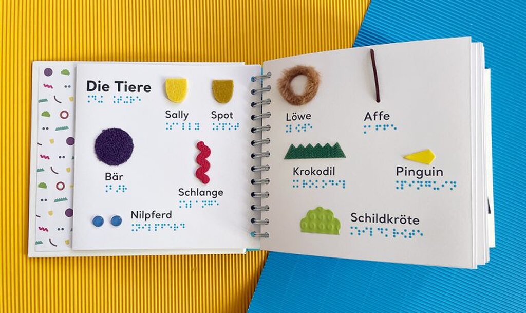 Geöffnetes Buch mit Großdruck und taktilen Abbildungen