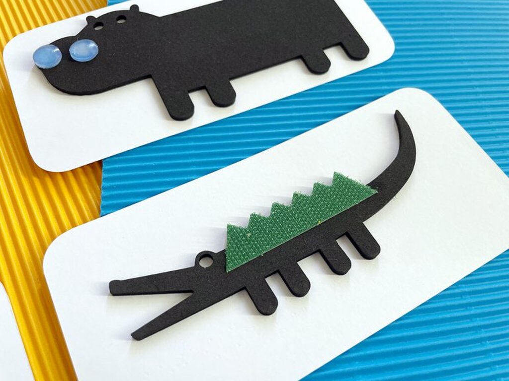 Zwei taktil gestaltete Spielkarten aus dem Buch: Oben ein Nilpferd, unten ein Krokodil.