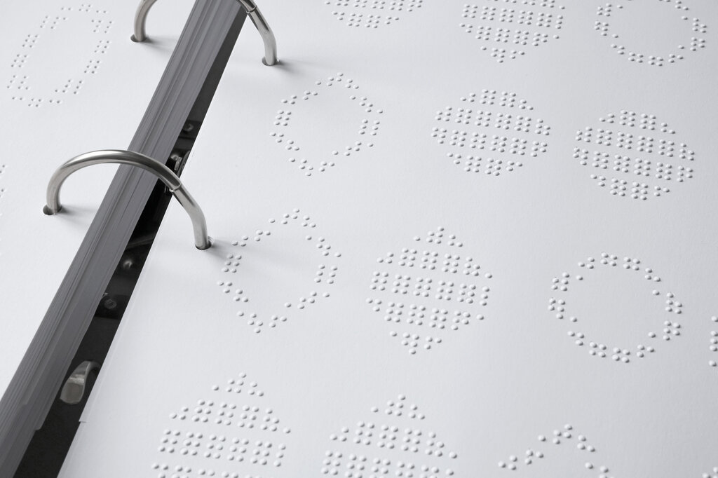 Detailaufnahme einer Seite mit tastbaren Formen und Mustern.