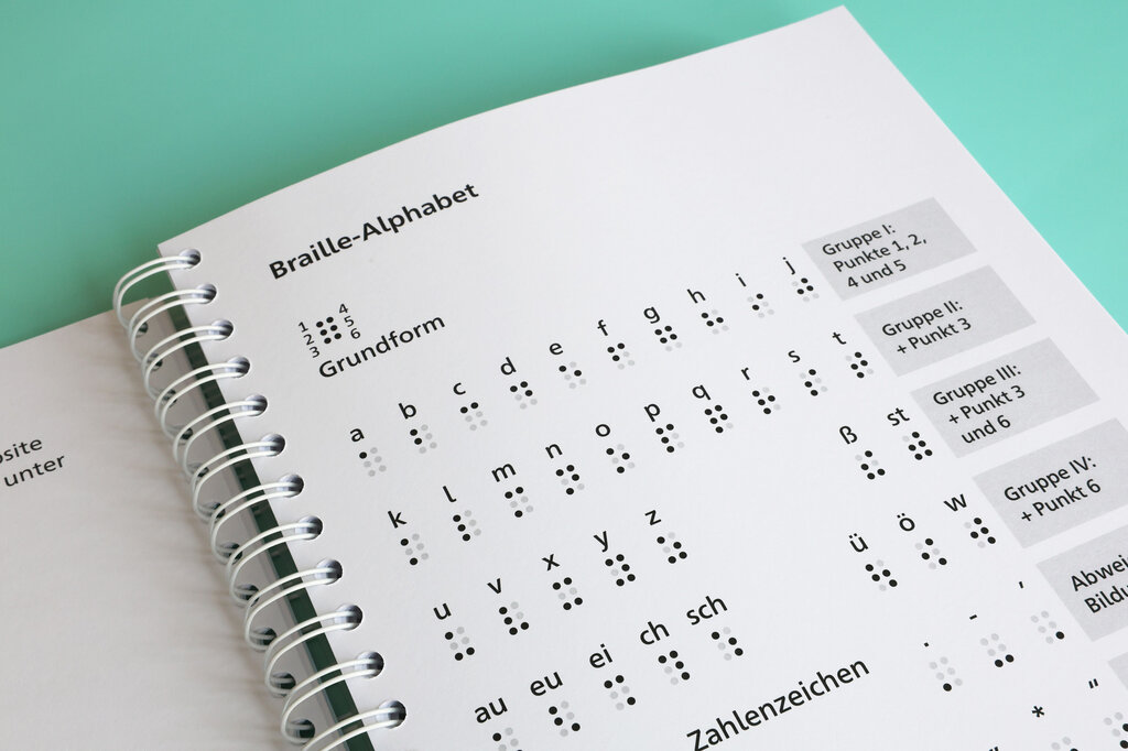 Aufgeschlagenes Ringbuch mit einer Übersicht des Braille-Alphabets.