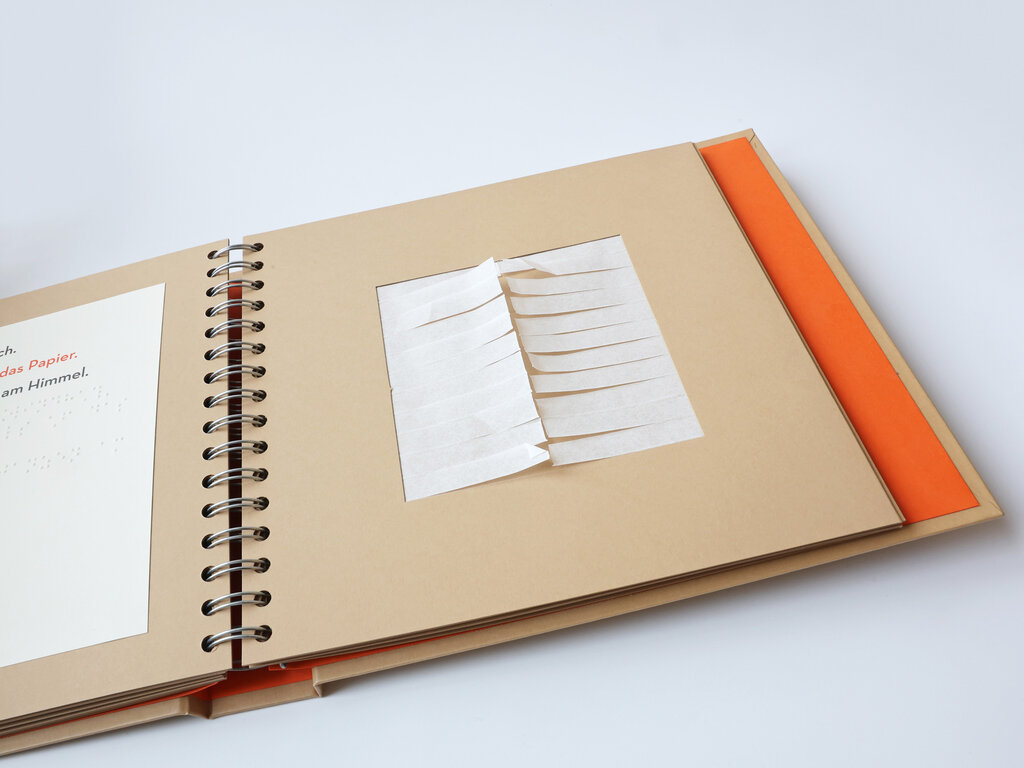 Aufgeklapptes Ringbuch mit einer taktil gestalteten Buchseite mit dünn geschnittenen Papierstreifen.